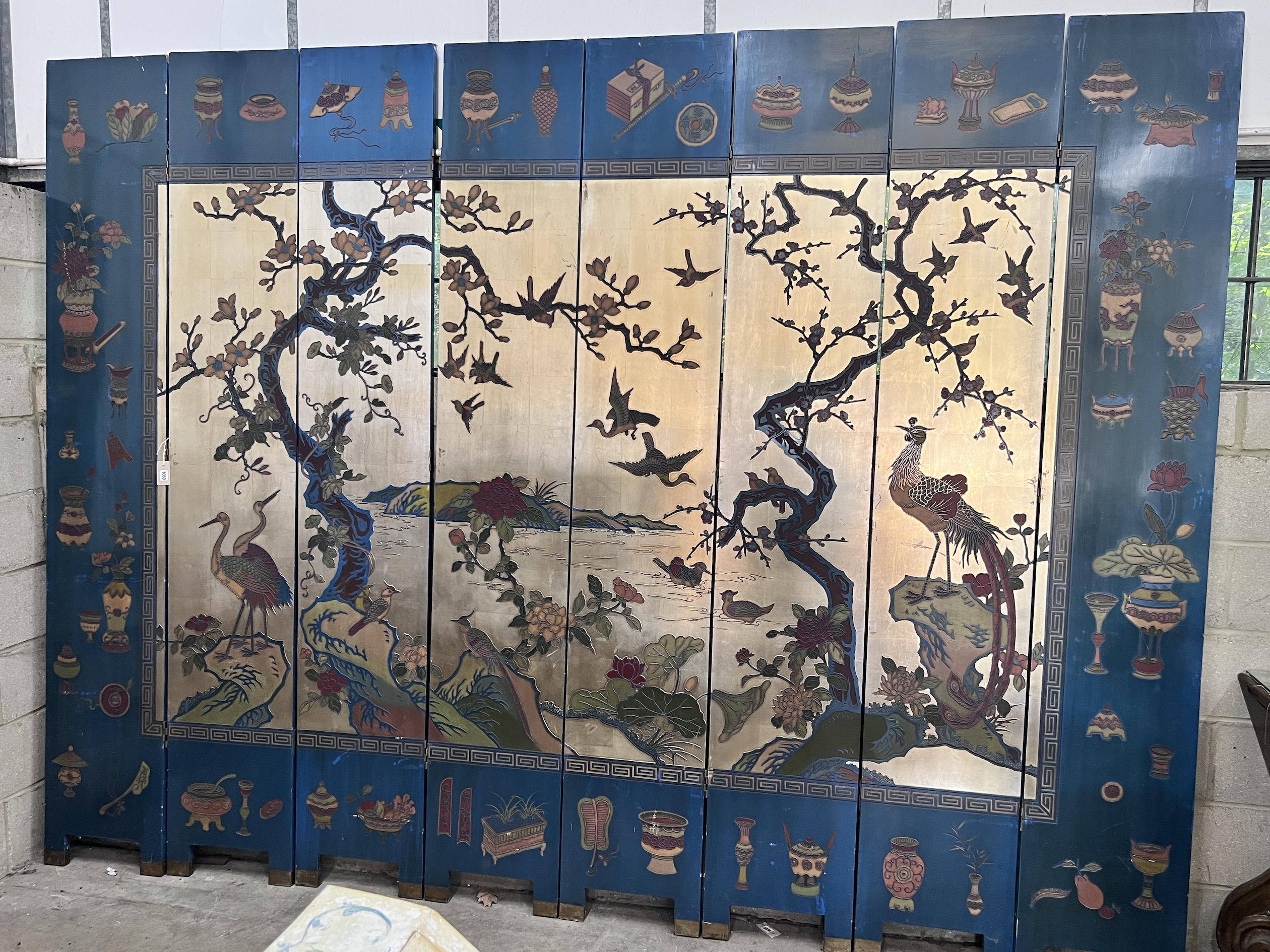 A Chinese lacquered eight fold screen decorated with exotic birds among flowering trees, each panel width 40cm, height 244cm (no fixing clips)